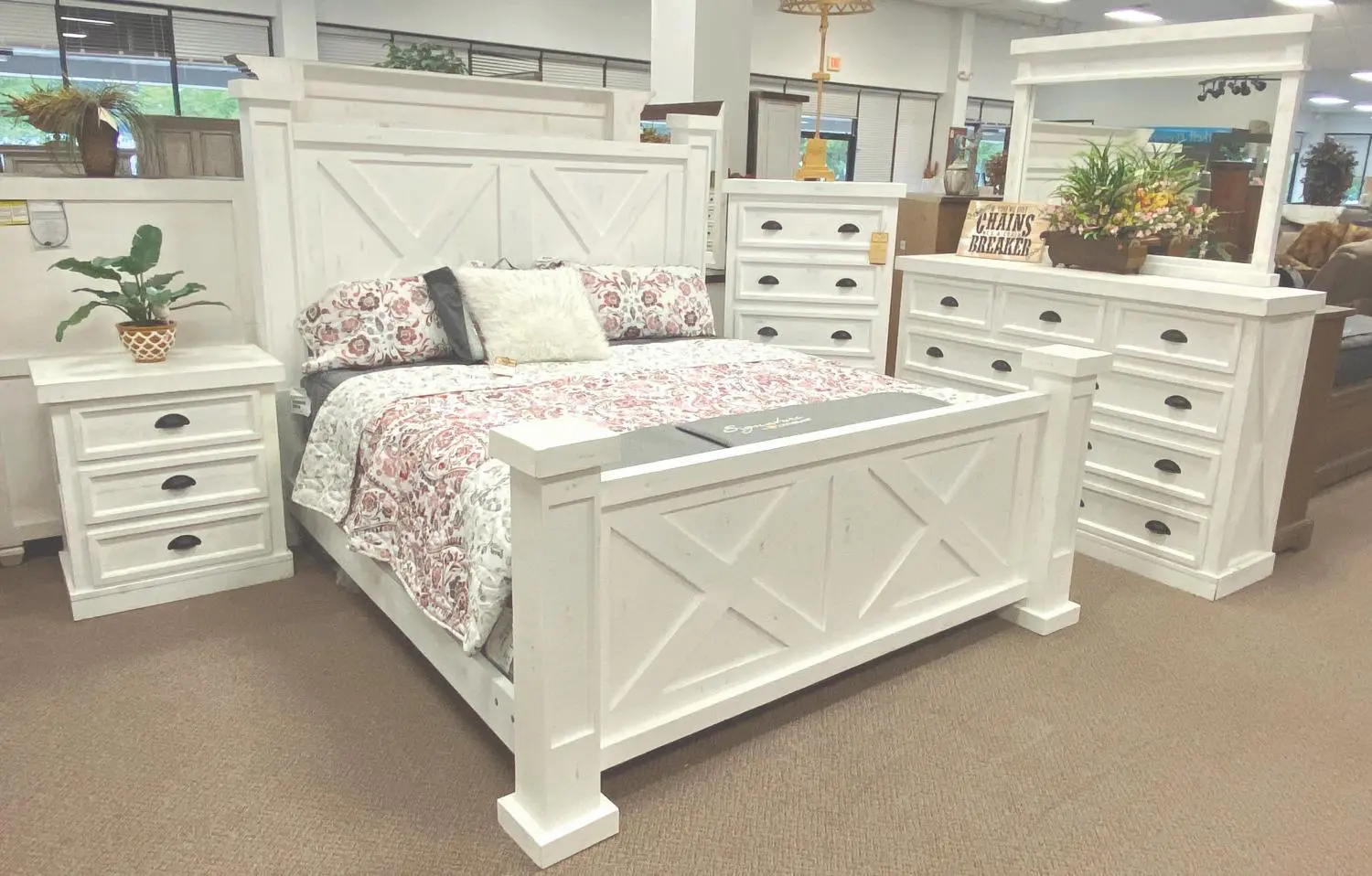 A white bed with floral bedding and dresser.