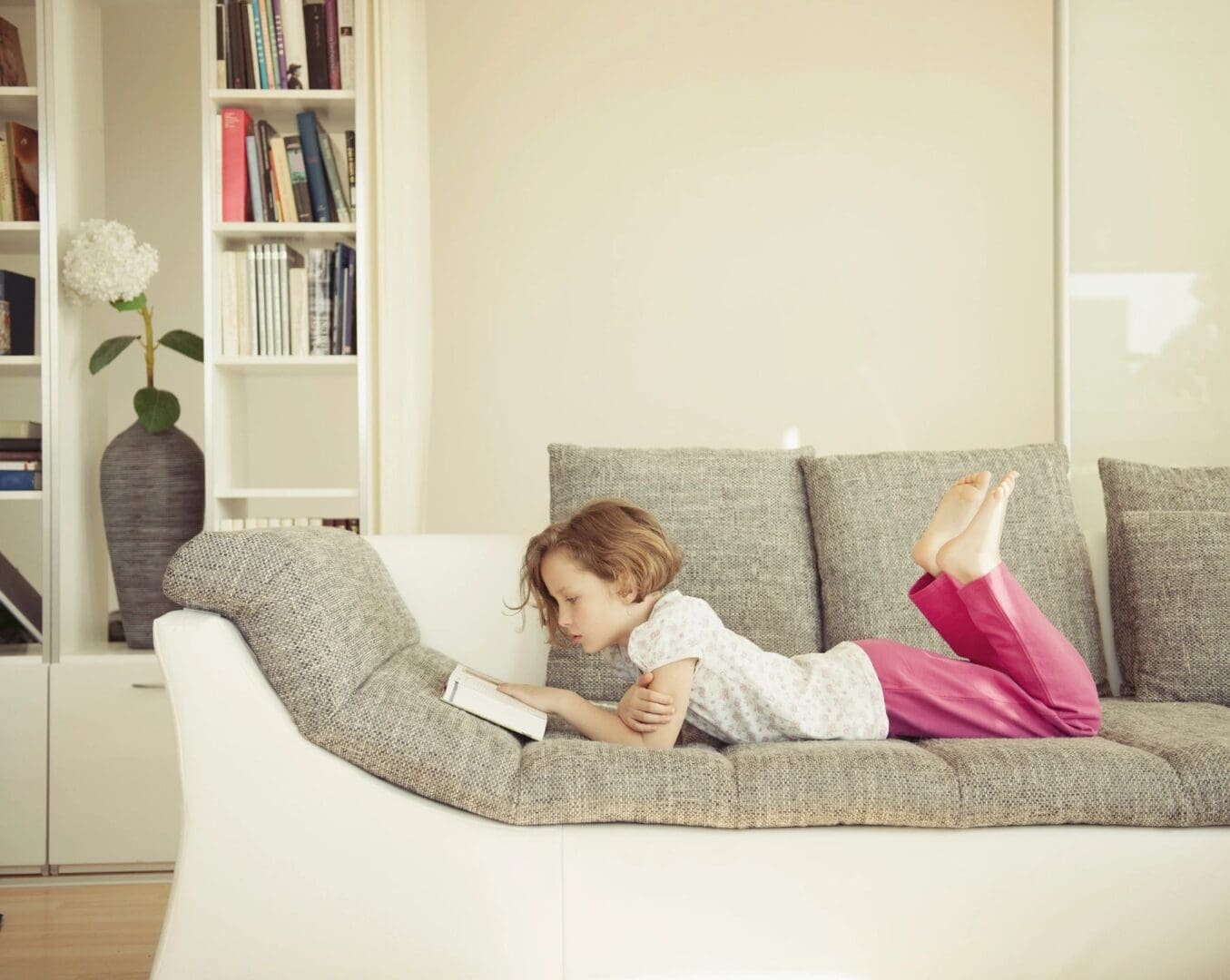 A little girl laying on the couch reading
