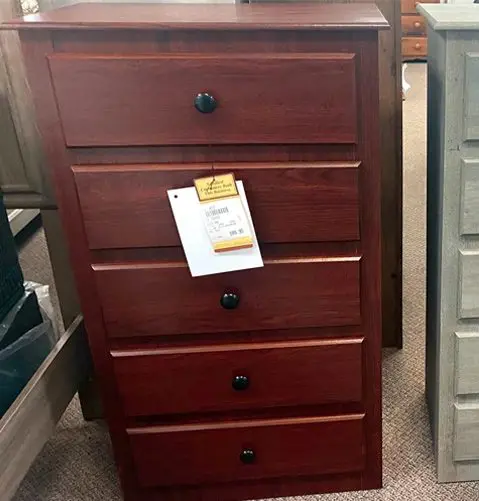 A chest of drawers with four drawers and black handles.